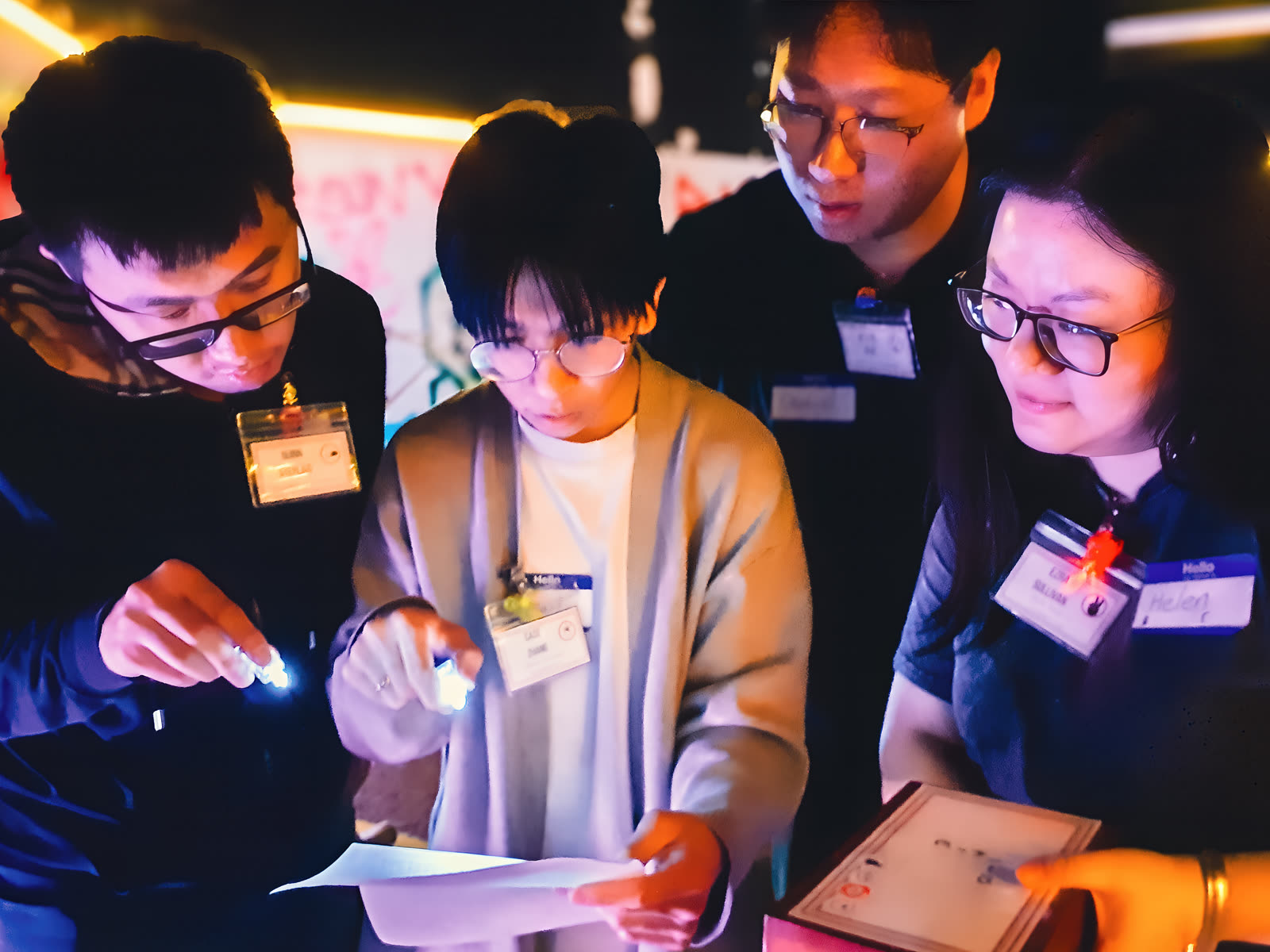 Four players examining evidence under flashlights in dramatic cross-lighting